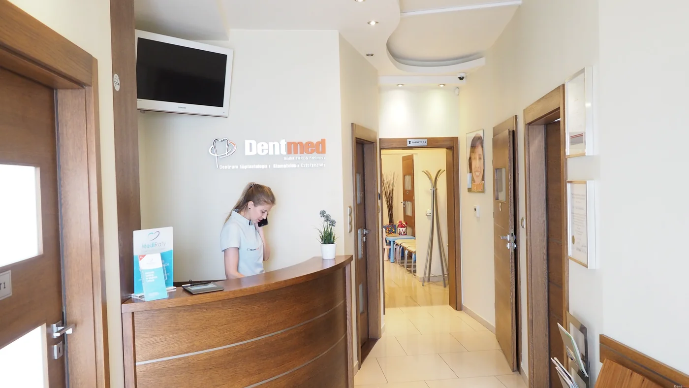 Osoba przy drewnianej ladzie recepcji Dentmed